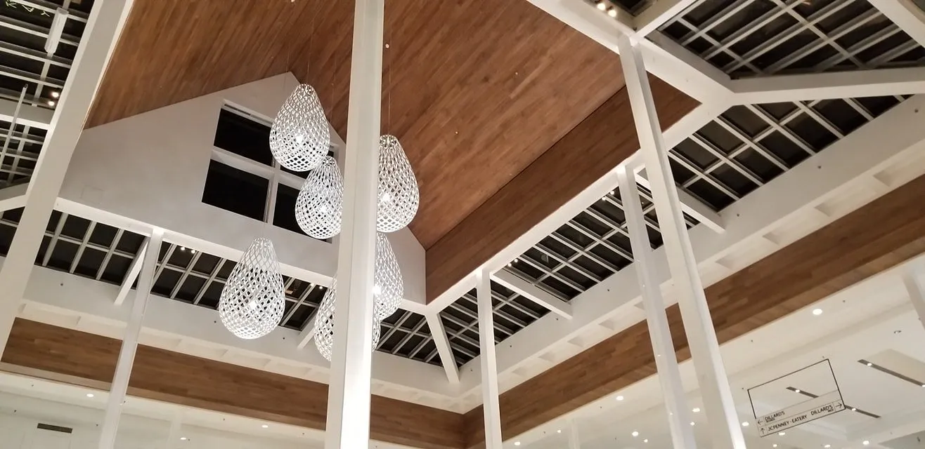 Dramatic wood-clad angular ceiling with pendant lights over a mall commons