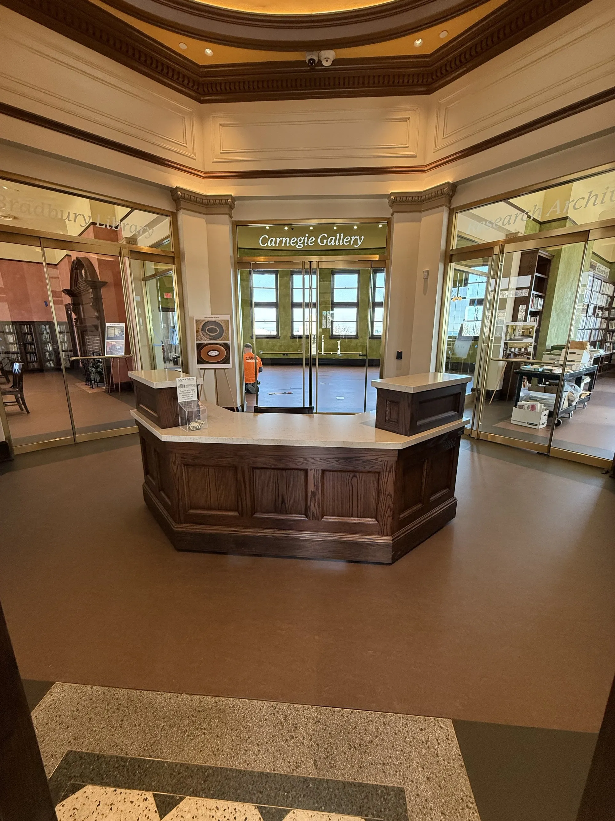 Custom octagonal library circulation desk in raised-panel oak with a solid-surface top under a coffered rotunda