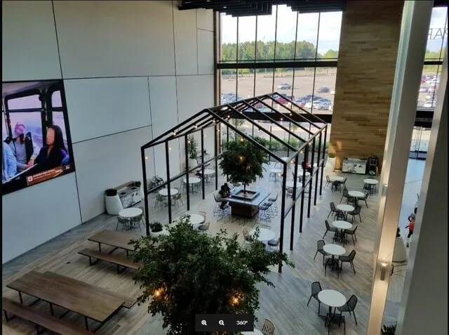 Corporate cafe commons with a glass-house structure, wood slat feature wall, and custom seating