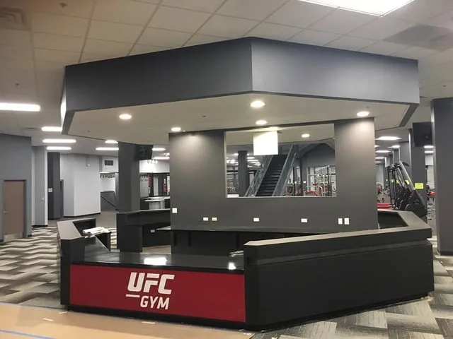 Custom fitness club reception desk with a dark feature canopy overhead