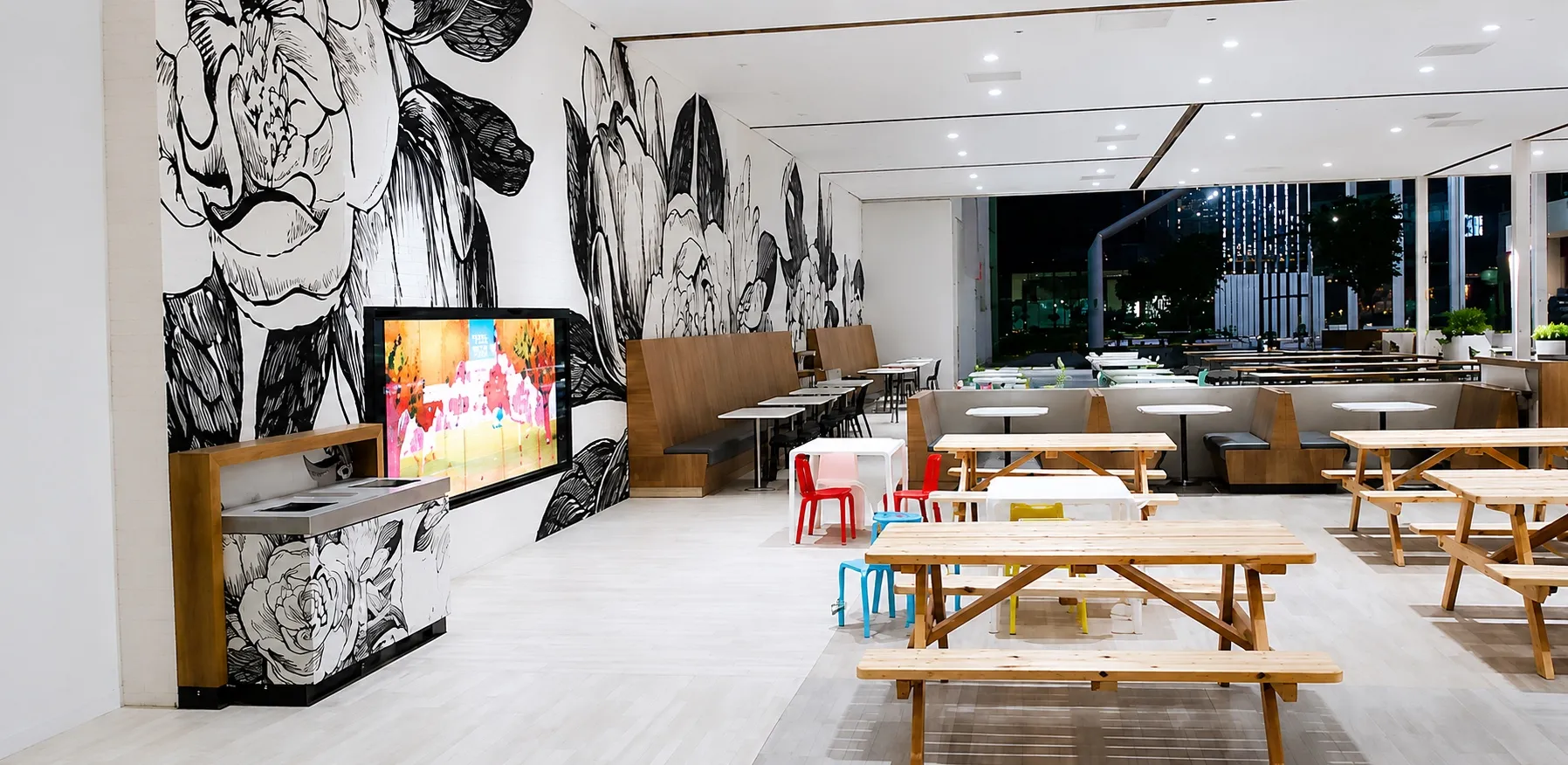 Commercial food-hall interior with custom wood booth seating, banquettes, and a black-and-white botanical mural feature wall