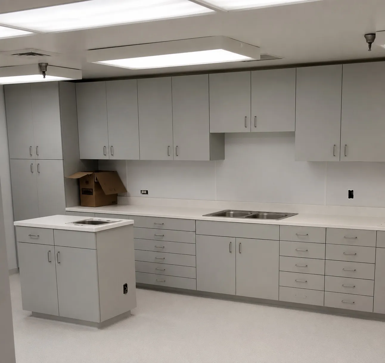 Grey plastic-laminate lab casework with full base and upper cabinet runs and a peninsula sink