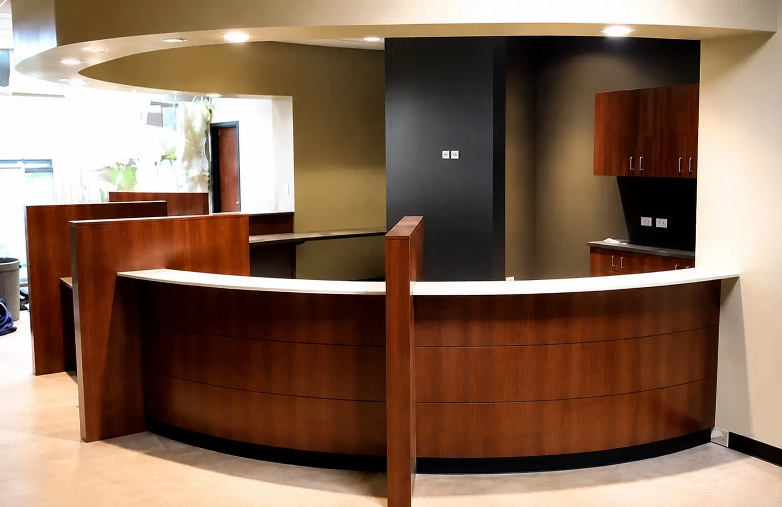 Curved cherry-wood reception desk with a black feature wall and white solid-surface top