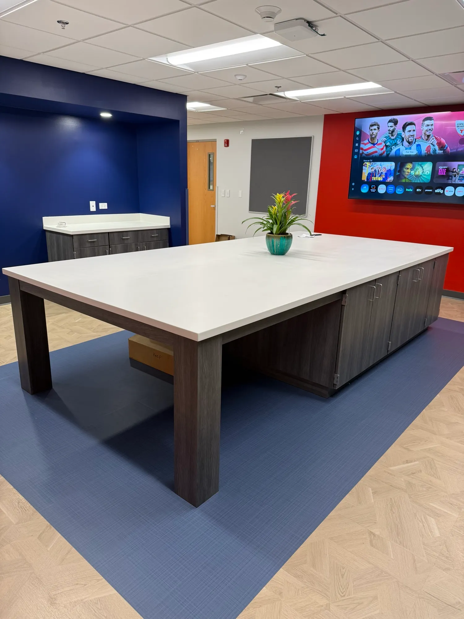 Solid-surface work island on grey-laminate base cabinets in a school workroom